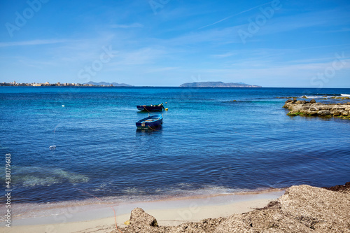 fishing boats moored on the beach with Trapani and the Egadi Islands in front with clear and transparent sea in an early summer day