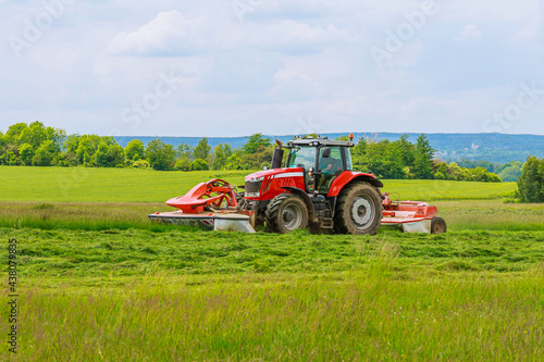 Big red tractor with two mowers mows the grass for silage photo