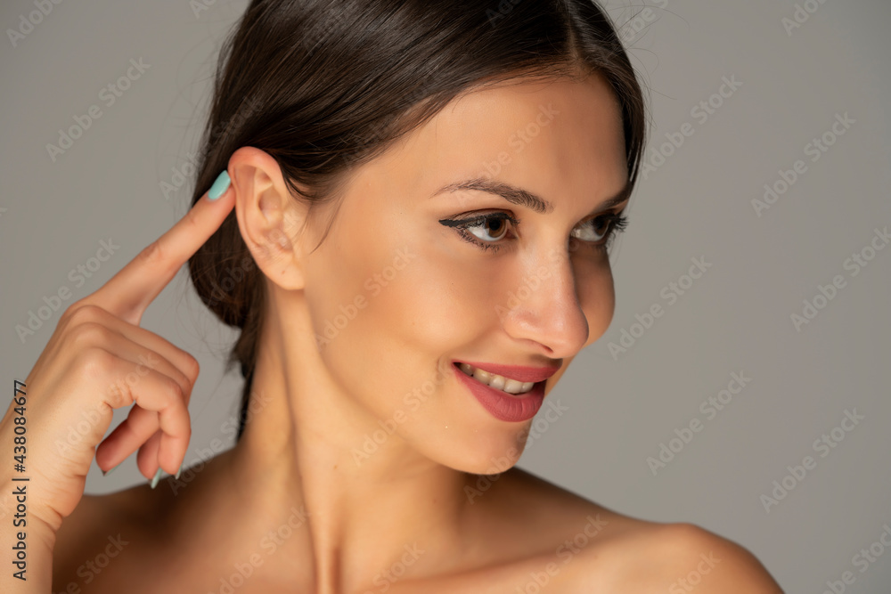 a young beautiful woman touches her ear