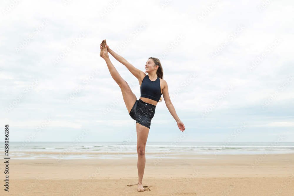 Blonde woman making yoga. She is in beach during cloudy sunset or sunrise. She is alone. She is wearing sportswear. She is caucasian girl from Germany Blonde woman making yoga. She is in beach during cloudy sunset or sunrise. She is alone. She is wearing sportswear. She is caucasian girl from Germany
