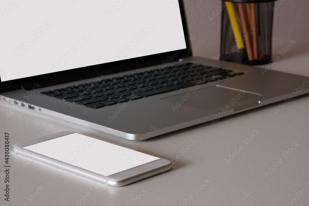 side view of wooden table with smartphone, laptop and stationery in home office room side view of wooden table with smartphone, laptop and stationery in home office room