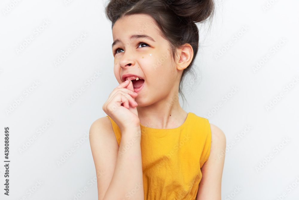 Studio portrait of a cute little girl showing teething baby tooth, isolated on grey studio background. A child has lost the first milk tooth. Kid losing primary baby teeth. Studio portrait of a cute little girl showing teething baby tooth, isolated on grey studio background. A child has lost the first milk tooth. Kid losing primary baby teeth.