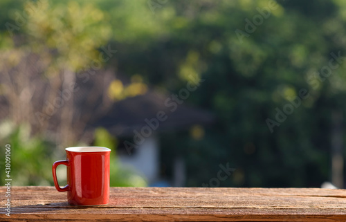 red cup of coffee with blur nature green background
