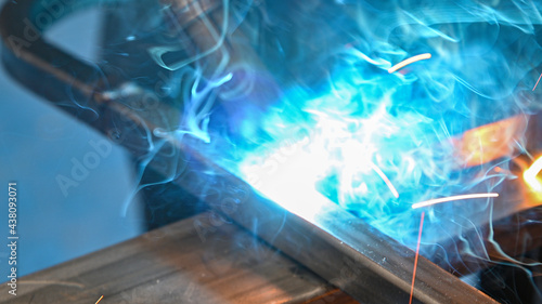 close up photo of the welding of two pieces of steel in a metal workshop, it is seen as a powerful white light comes out and sparks come out while the steel is welded