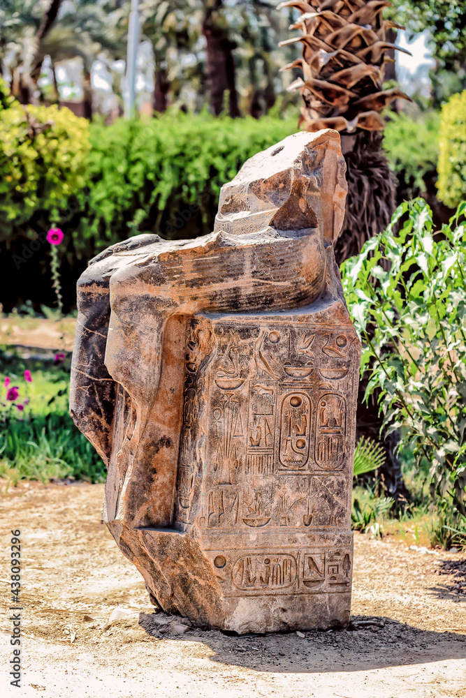 A broken Ancient Egyptian Statue hieroglyphics on its base.