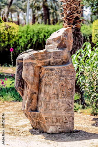 A broken Ancient Egyptian Statue hieroglyphics on its base.