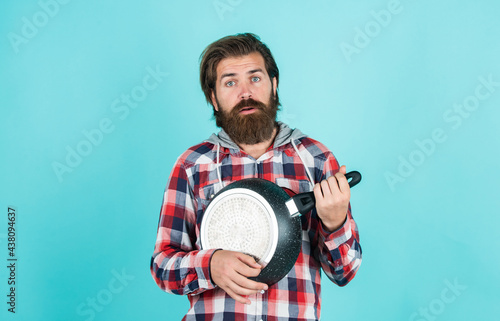 funny cooking. man holding frying pan.. male chef kitchener cooking. hipster checkered shirt for bearded guy cook. unshaven brutal man with kitchen utensil. household goods. friendly shop assistant