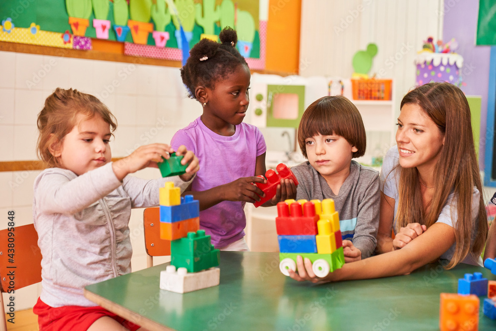 Naklejka premium Tagesmutter und Kinder spielen mit Bauklötzen