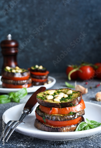 Eggplant and tomato appetizer with pesto sauce on a concrete kitchen table. Eggplant appetizer with nuts.