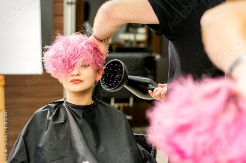 Hairdresser drying pink hair of client