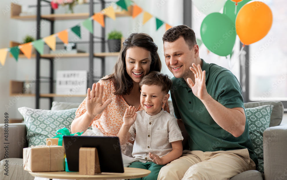 Fototapeta premium family, holidays and people concept - portrait of happy mother, father and little son with tablet pc computer and birthday gifts on table having video call at home party