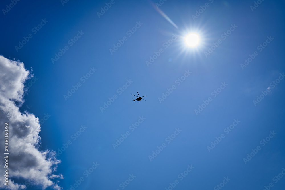 Silhouette of a helicopter against a blue sky with clouds Silhouette of a helicopter against a blue sky with clouds