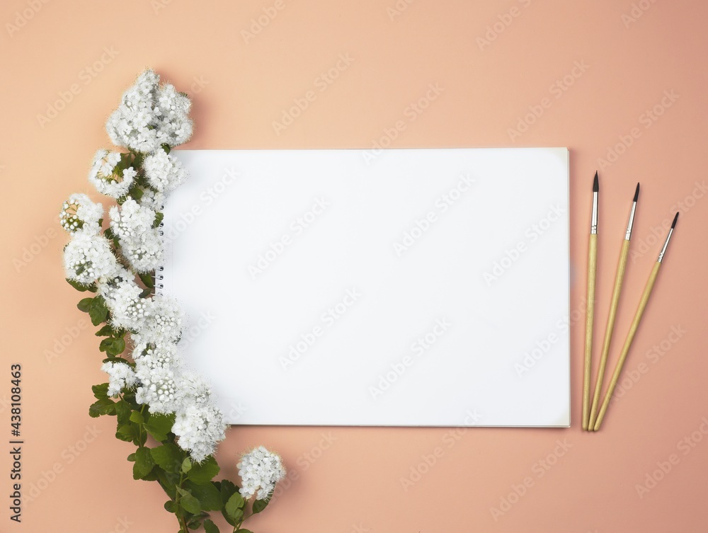 School album on a pink background. White flowers.Flowers on a white album and on a pink background. Brushes on a pink background and with a sketchbook. white scrapbook. flat lay. back to school. Schoo
