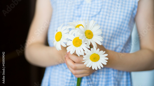 Little girl holding a bouquet of daisies in her hands. Image with selective focus