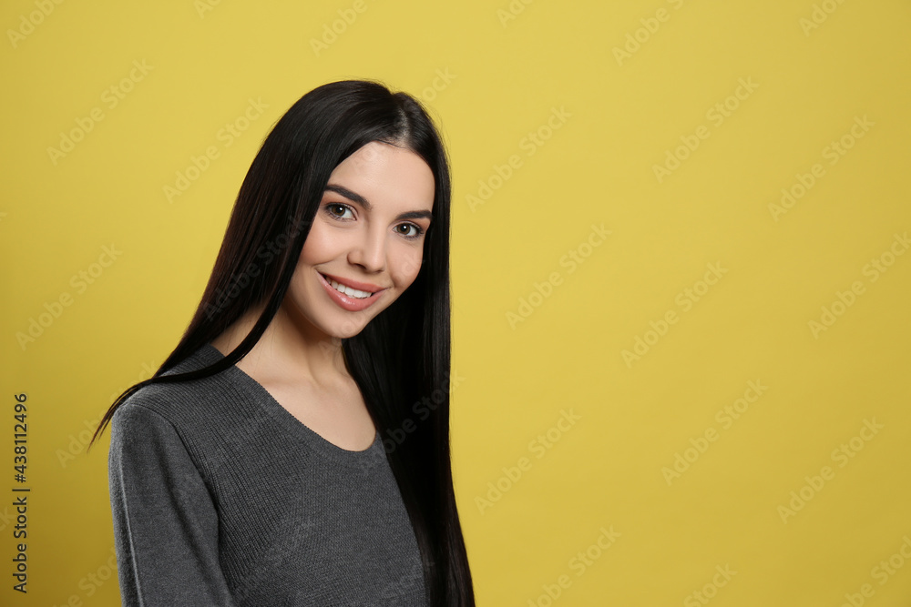 Portrait of happy young woman with beautiful black hair and charming smile on yellow background, space for text Portrait of happy young woman with beautiful black hair and charming smile on yellow background, space for text