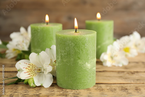 Burning candles and beautiful flowers on wooden table