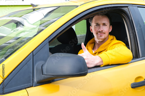 happy male taxi driver sits behind the wheel of a taxi