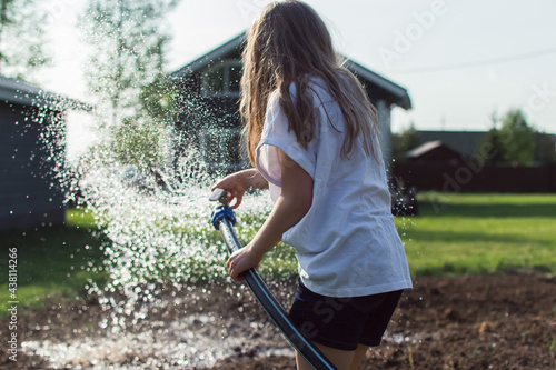 girl is hosing down a vegetable garden