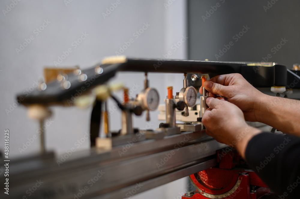 Black electrical guitar in repair service shop with a hands of a guitar luthier Black electrical guitar in repair service shop with a hands of a guitar luthier