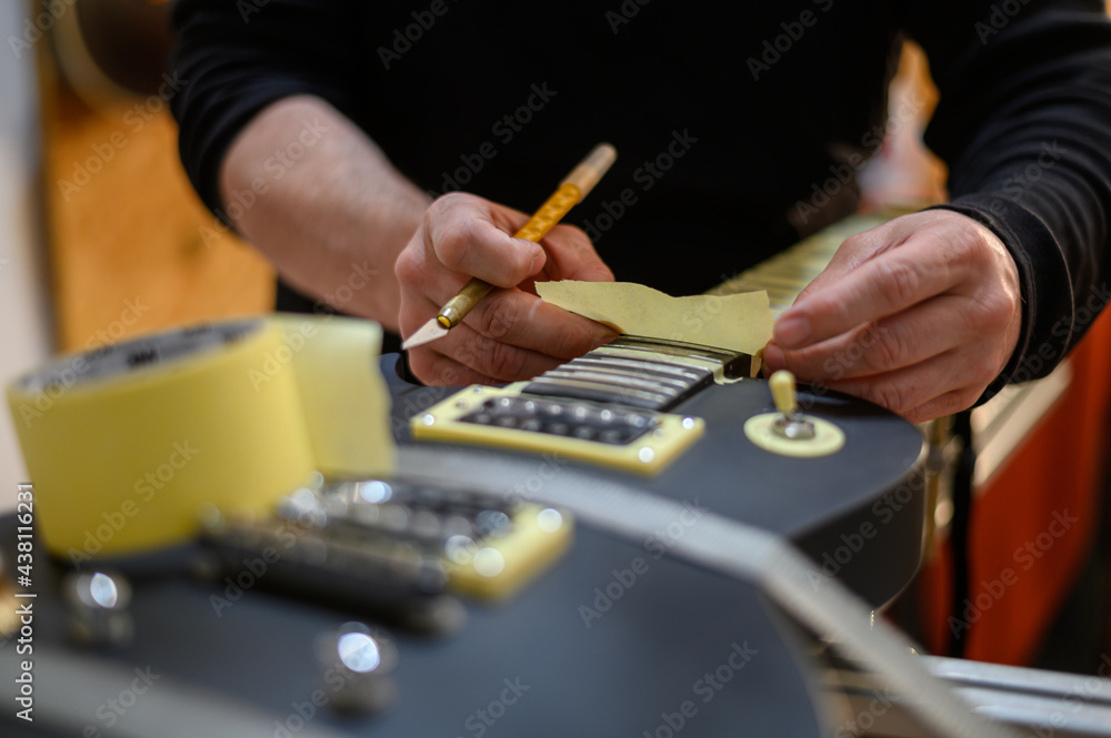 Black electrical guitar in repair service shop with a hands of a guitar luthier Black electrical guitar in repair service shop with a hands of a guitar luthier