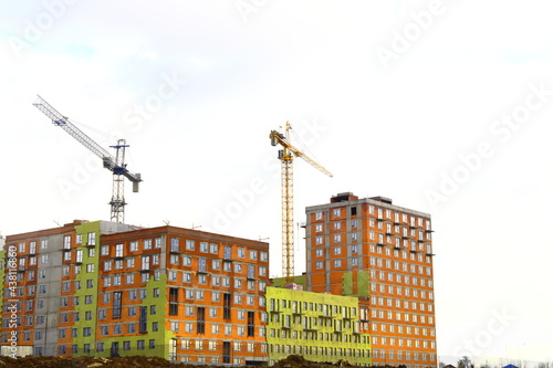 Photography Construction cranes over buildings under construction in red and green, Moscow r