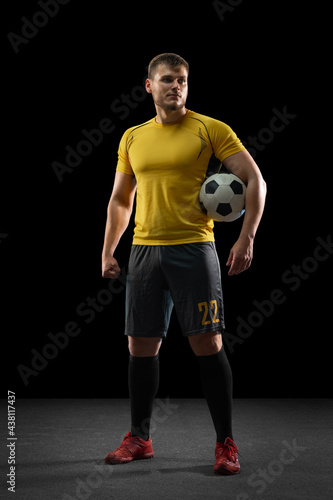 Professional caucasian football soccer player standing isolated on black studio background. © master1305