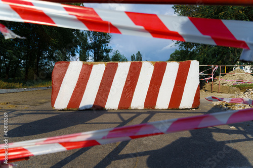 concrete block with red and white striped lines as a roadblock, traffic is prohibited and road works, the road is closed for maintenance