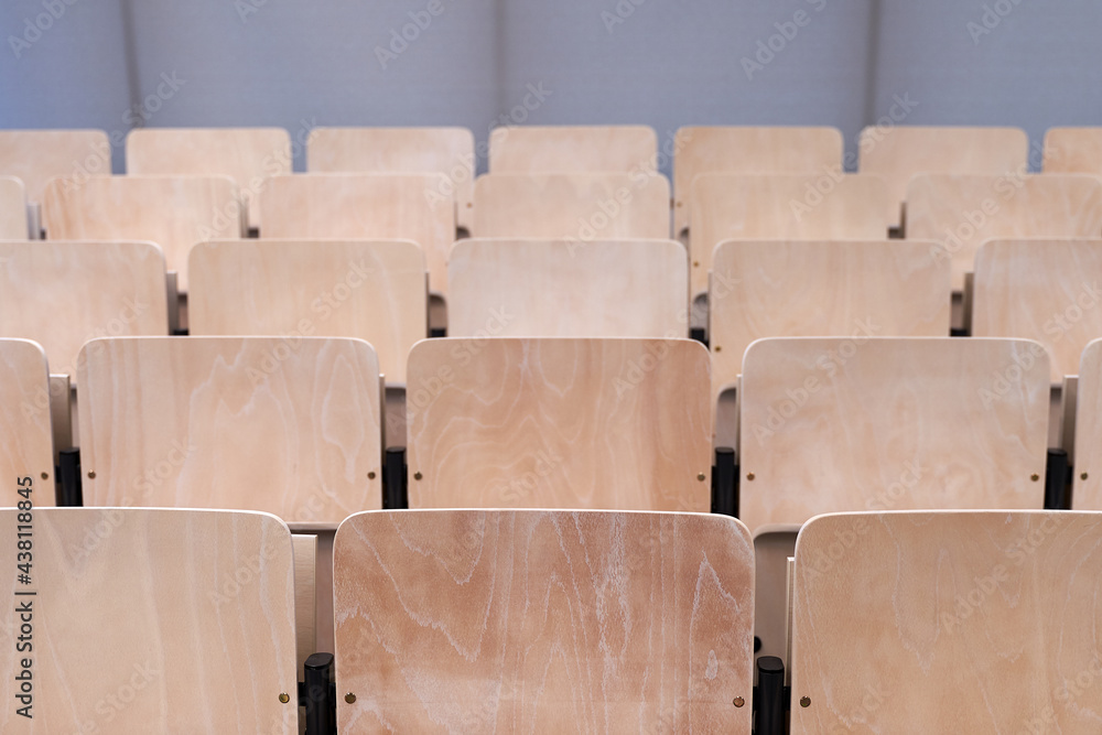 Empty collapsible wooden chairs in auditorium background. Higher education at university or college.