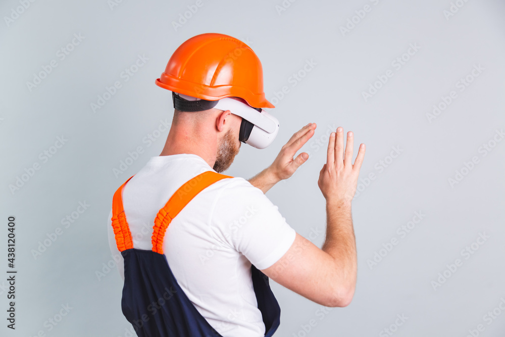 Handsome man engineer in building protective helmet and vr glasses on gray background touching air Handsome man engineer in building protective helmet and vr glasses on gray background touching air
