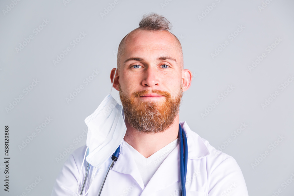Handsome male doctor on gray background with takes off protective medical mask Handsome male doctor on gray background with takes off protective medical mask