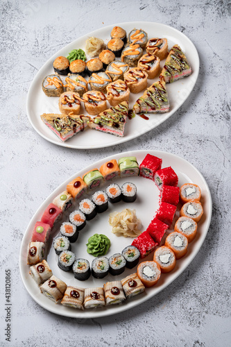 Two big trays of assorted sushi rolls on white stone background, studio light, top view above photo