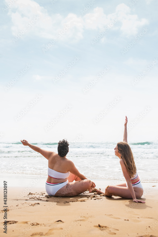 Anonymous ladies in swimwear on sandy beach near sea Anonymous ladies in swimwear on sandy beach near sea