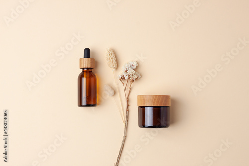 Minimal composition with cosmetic skin care products and flowers on pastel beige background. Flat lay. photo