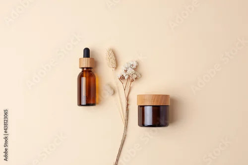 Obraz Minimal composition with cosmetic skin care products and flowers on pastel beige background. Flat lay.