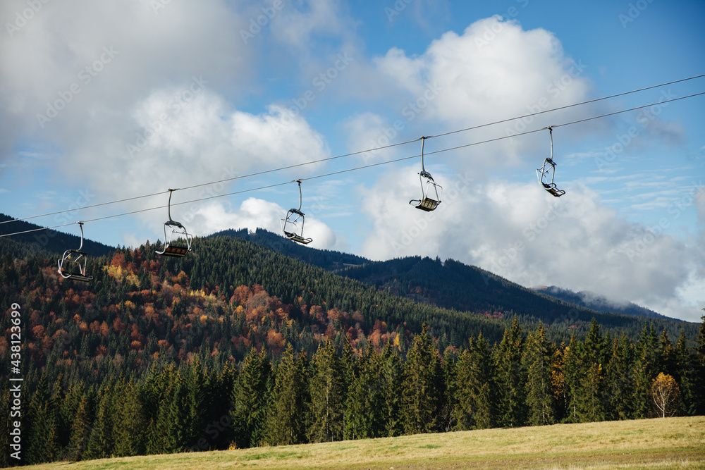Low angle view of ski lift among mountains with green forest