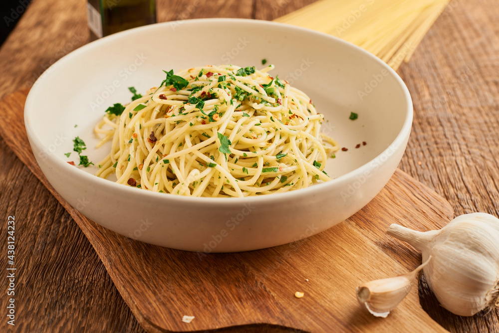 Plate with cooked traditional Italian spaghetti aglio olio on wooden table Plate with cooked traditional Italian spaghetti aglio olio on wooden table