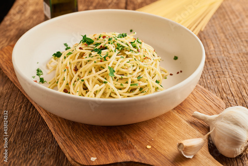 Plate with cooked traditional Italian spaghetti aglio olio on wooden table