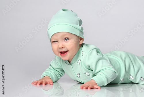 charming boy in a sprawling and sliders and a hat. Newborn baby is resting. Baby Todler joyfully smiles and winks to you.