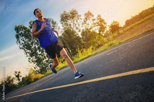 Silhouette of Young man running sprinting on road. Fit runner fitness runner during outdoor workout with sunset background. Selected focus © Panumas
