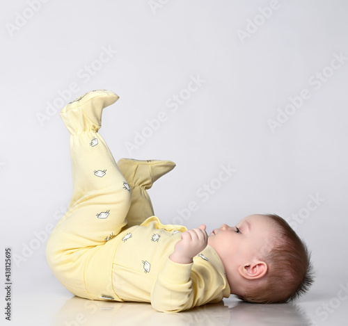 Fotografía Baby lying on his back, happy infant wearing a yellow bodysuit jumpsuit, beautif