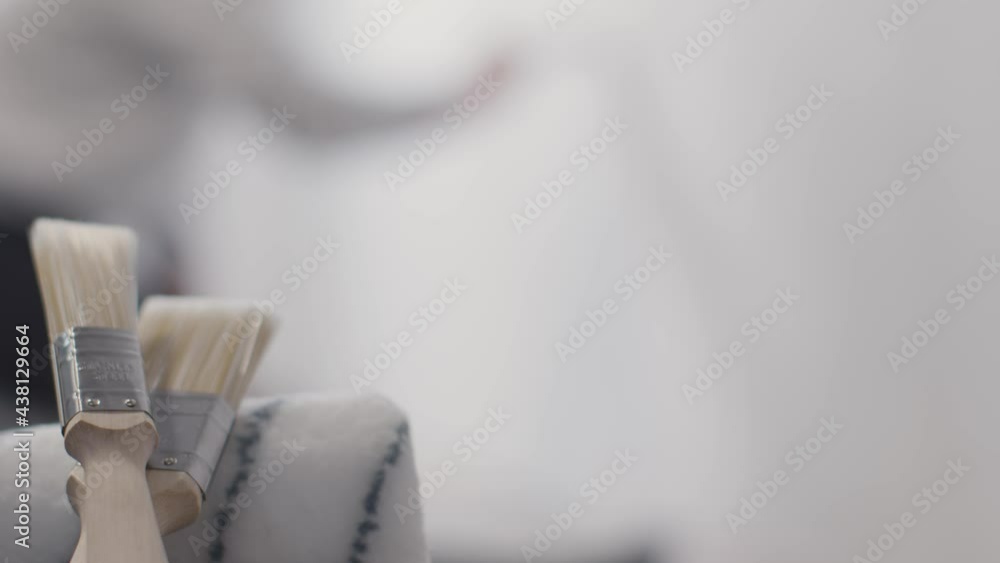 Pull Focus Shot of a Person Painting White Wall with Paint Brush Pull Focus Shot of a Person Painting White Wall with Paint Brush