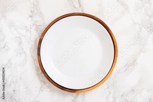 White plate in natural wooden plate on marble table
