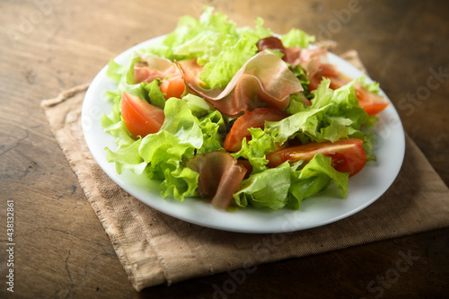 Healthy green salad with tomato and prosciutto