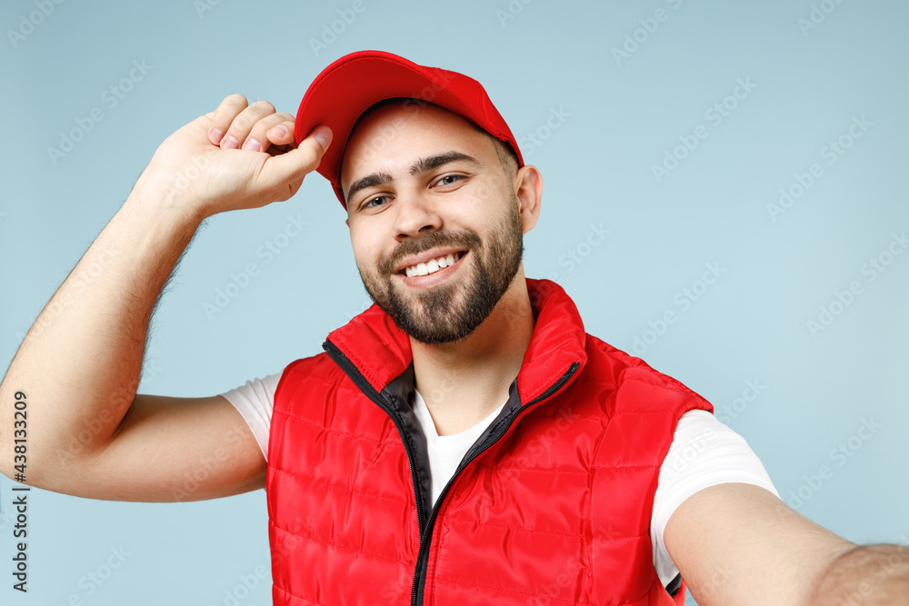 Close up professional delivery guy employee man in red cap white T-shirt uniform workwear work as dealer courier doing selfie isolated on pastel blue color background studio portrait. Service concept. Close up professional delivery guy employee man in red cap white T-shirt uniform workwear work as dealer courier doing selfie isolated on pastel blue color background studio portrait. Service concept.