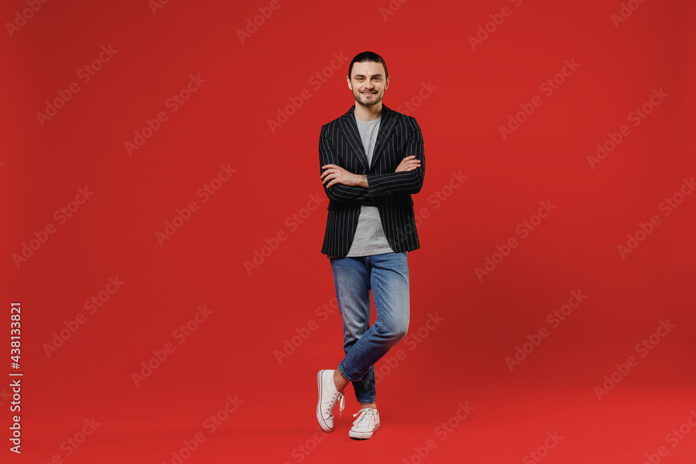 Full length young smiling businessman latin man 20s with long hair ponytail wearing black striped jacket grey shirt look camera hold hands crossed folded isolated on red background studio portrait Full length young smiling businessman latin man 20s with long hair ponytail wearing black striped jacket grey shirt look camera hold hands crossed folded isolated on red background studio portrait