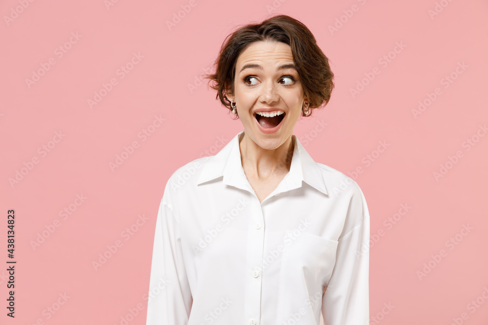 Young fun amazed impressed shocked successful employee business woman corporate lawyer 20s wear classic formal white shirt work in office look aside isolated on pastel pink background studio portrait.