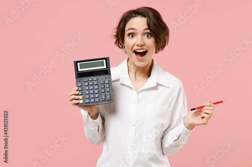 Young smiling successful employee business secretary woman corporate lawyer in classic formal white shirt work in office hold in hands calculator isolated on pastel pink background studio portrait photo