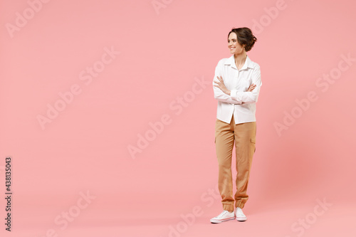 Full length young smiling happy successful employee business woman corporate lawyer in classic formal white shirt work in office hold hand crossed look aside isolated on pastel pink background studio