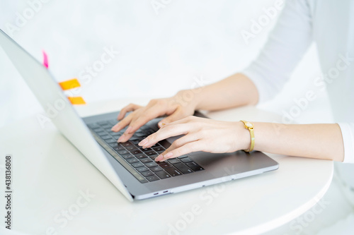 明るい部屋でノートパソコンを操作する女性の手元