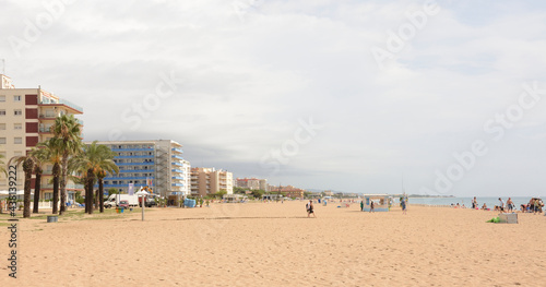 Fototapeta Naklejka Na Ścianę i Meble -   Tourists walking and sunbathing on the beach